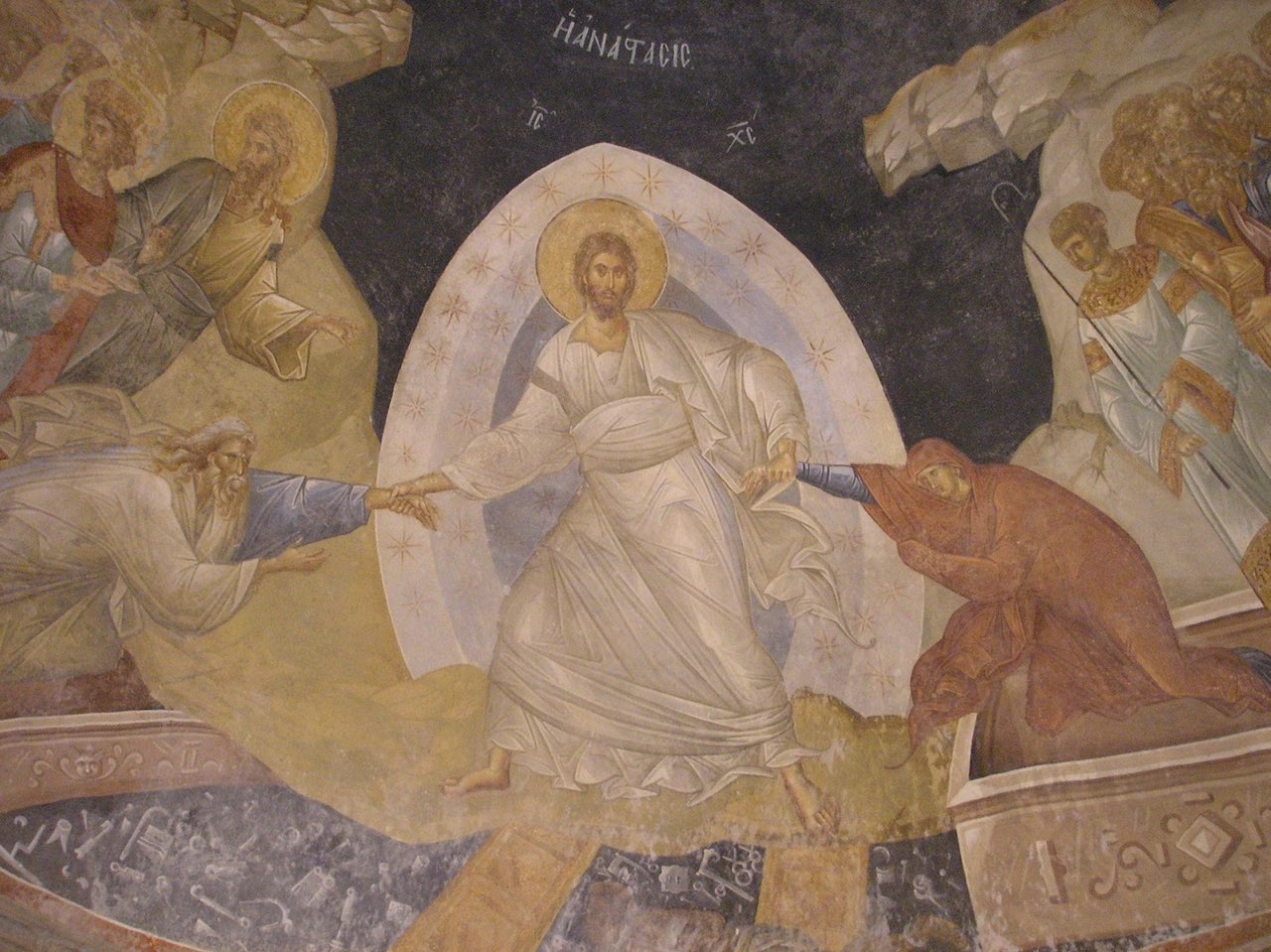 Byzantine fresco depicting the Resurrection of Christ, with Jesus in white robes at the center, emanating a golden halo, reaching out to figures clad in draped garments, set against a celestial background with inscriptions in Greek characters.